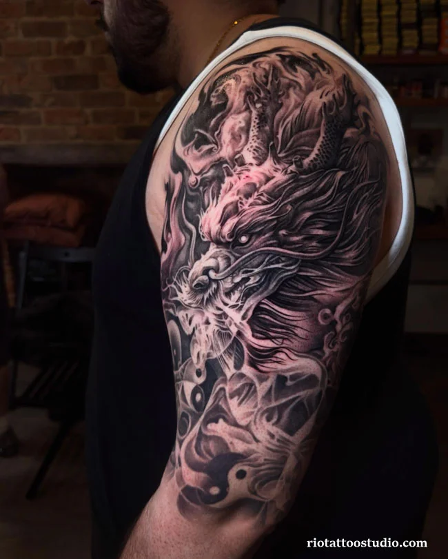 Hình xăm bắp tay nam Rồng Châu Á cuộn khói đen xám dũng mãnh chạm khắc tại Rio Tattoo Studio.