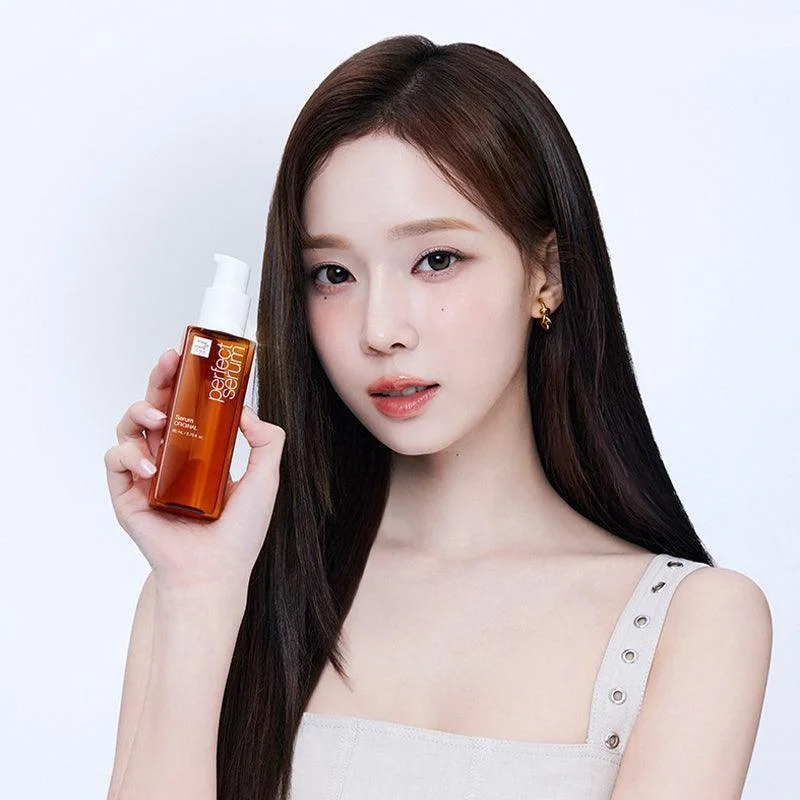 Ảnh bìa Facebook mỹ phẩm với nữ người mẫu cầm chai tinh chất chăm sóc da màu cam trên nền trắng sáng