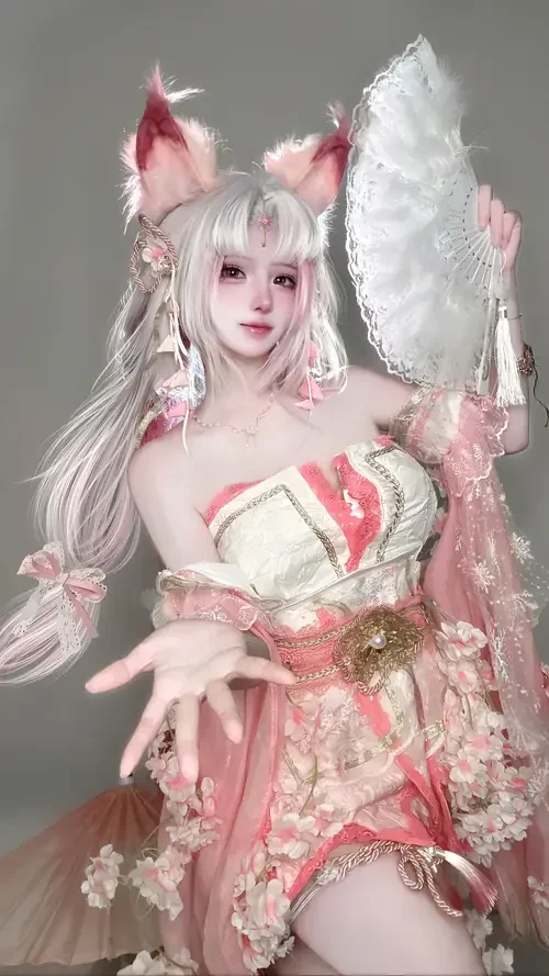 Bộ váy trắng hồng nổi bật, cô gái tóc bạc đội tai cáo đứng tạo dáng trong studio xám