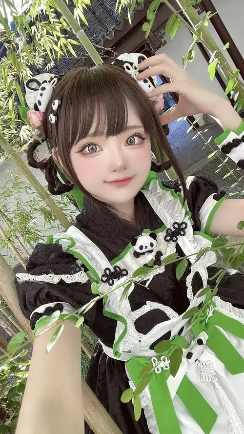 Cô nàng đội tai nghe đen tạo dáng giữa lá cây, mặc váy xanh cosplay với nụ cười nhẹ