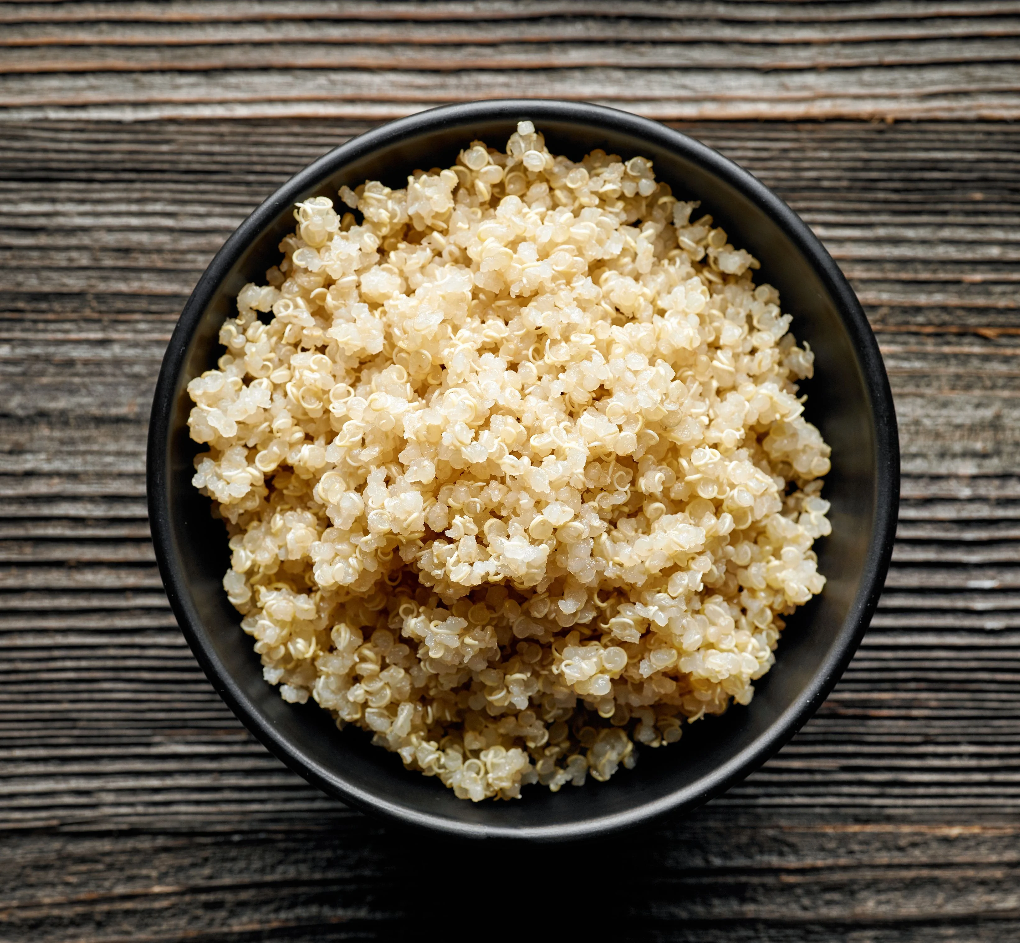 Bát quinoa chín đặt trên bàn gỗ tối màu