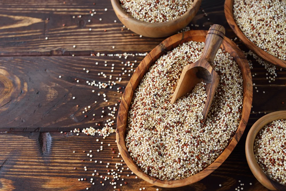 Hạt quinoa trong bát gỗ trên nền gỗ tối màu