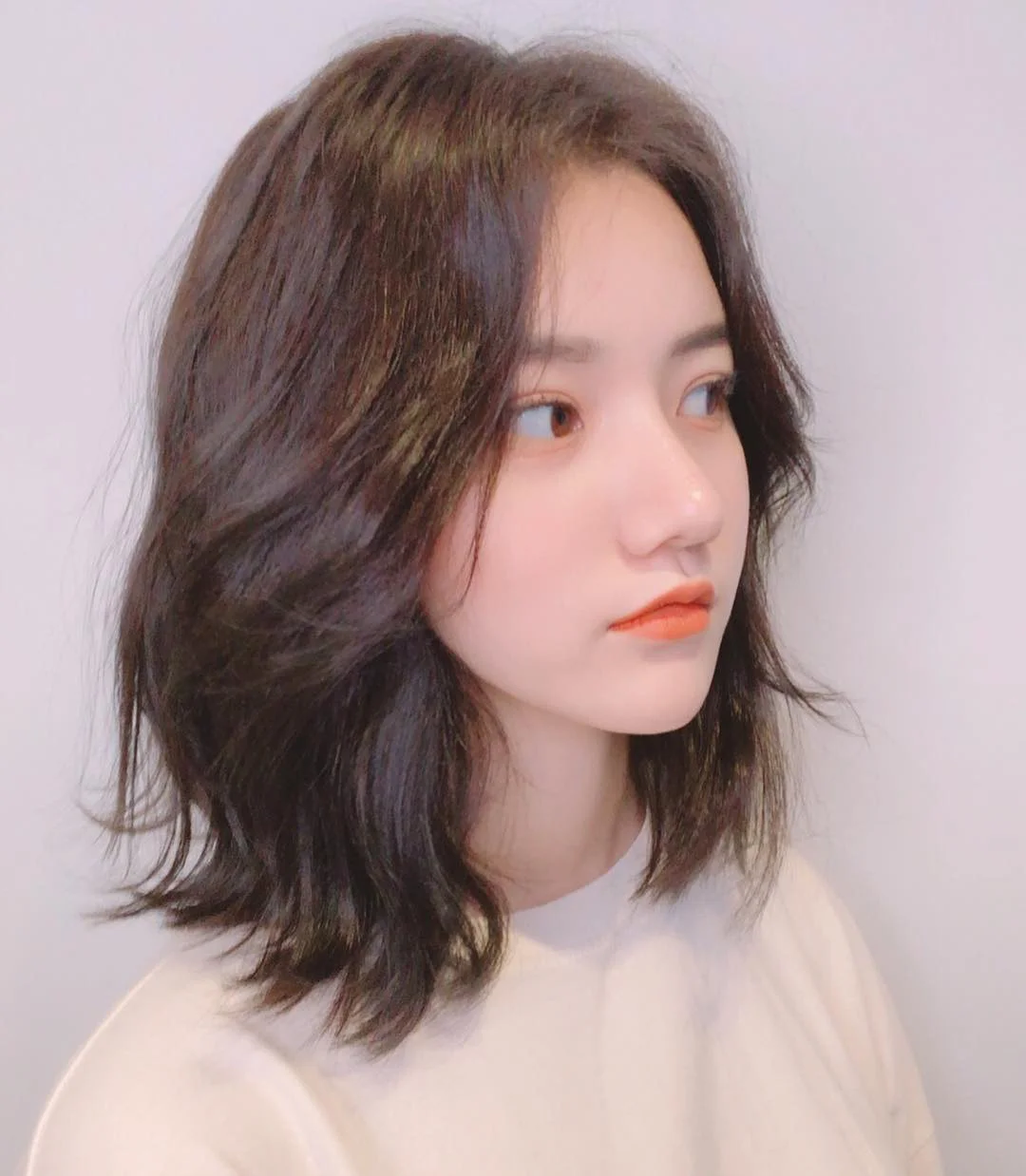 Tóc ngang vai xoăn sóng lơi màu nâu, nhìn nghiêng thanh thoát